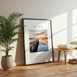 Exodus 14:14 - Be Still scripture verse print with calm lake sunset, wooden dock and small boat in soft blue and gold tones.