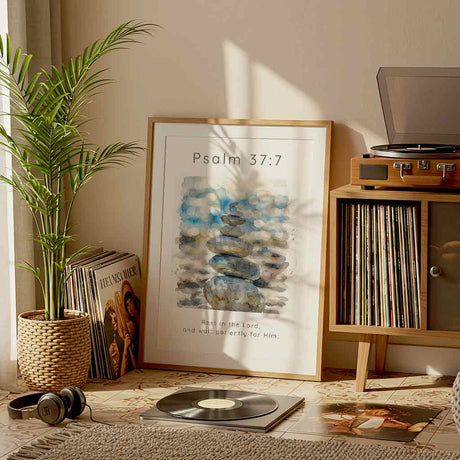 Psalm 37:7 - Christian artwork featuring balanced stone stack beside water in soft blue, grey and sandy watercolour tones.