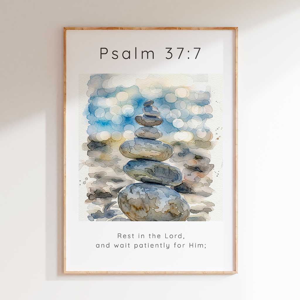 Psalm 37:7 - Christian art print with watercolour stacked pebbles and soft blue bokeh background and Rest In The Lord scripture verse.