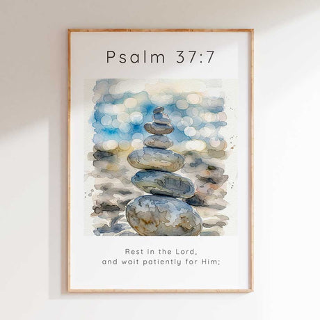 Psalm 37:7 - Christian art print with watercolour stacked pebbles and soft blue bokeh background and Rest In The Lord scripture verse.